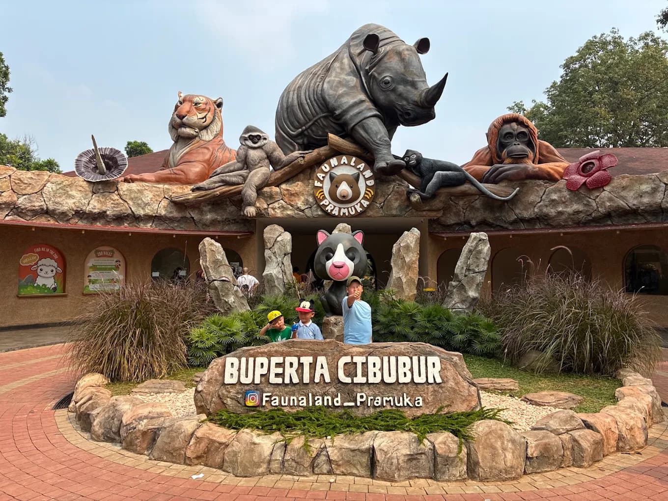 Gerbang utama Faunaland Buperta Cibubur dengan patung satwa dan papan nama taman